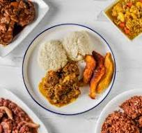 Plate of food with rice, meat, and fried plantains, surrounded by other dishes.