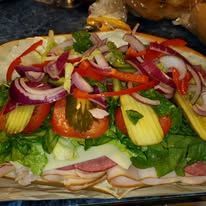 Sub sandwich loaded with lettuce, tomato, onions, and peppers. 