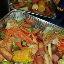 Crab legs, sausage, corn, and vegetables in a foil tray.