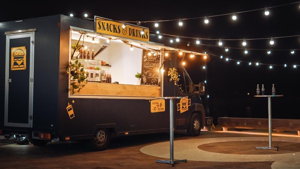 Food truck at night, illuminated by string lights.