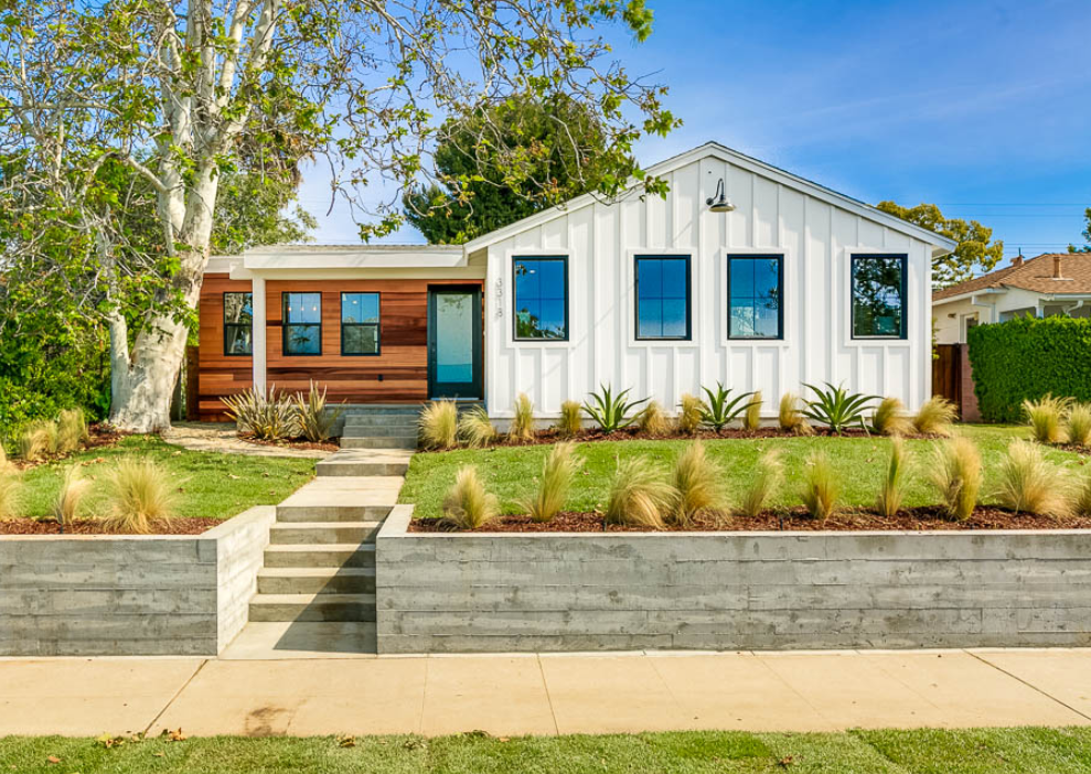 A white house with a blue door is sitting on top of a lush green lawn.