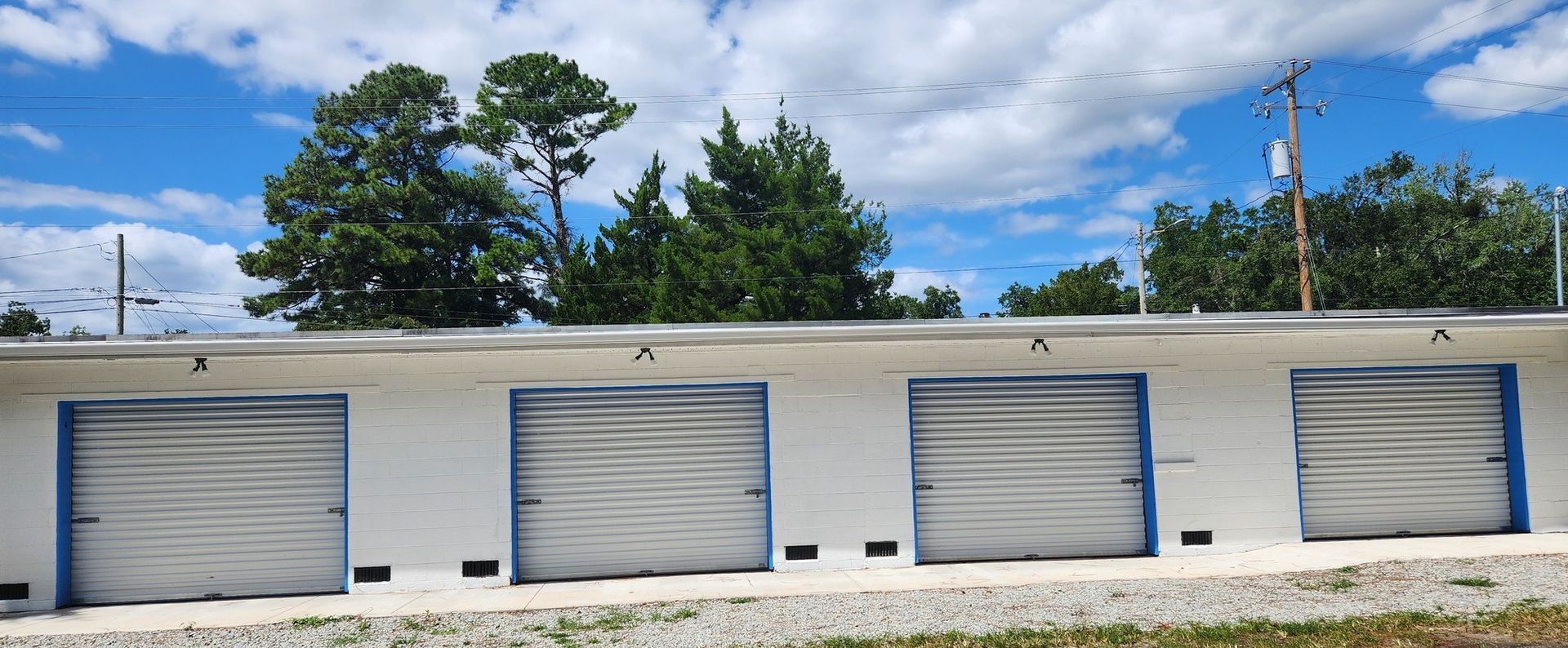 A row of garage doors on a building with trees in the background