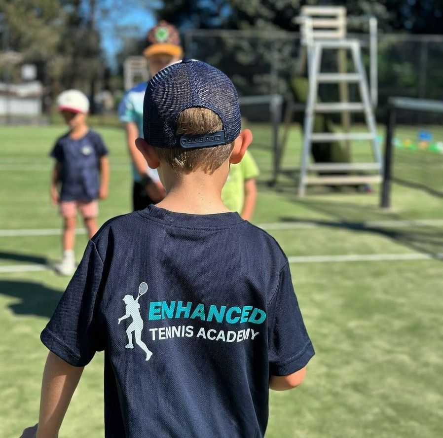 A Boy Wearing a Shirt That Says Enhanced Tennis Academy — Fab Art in Wallabi Point, NSW