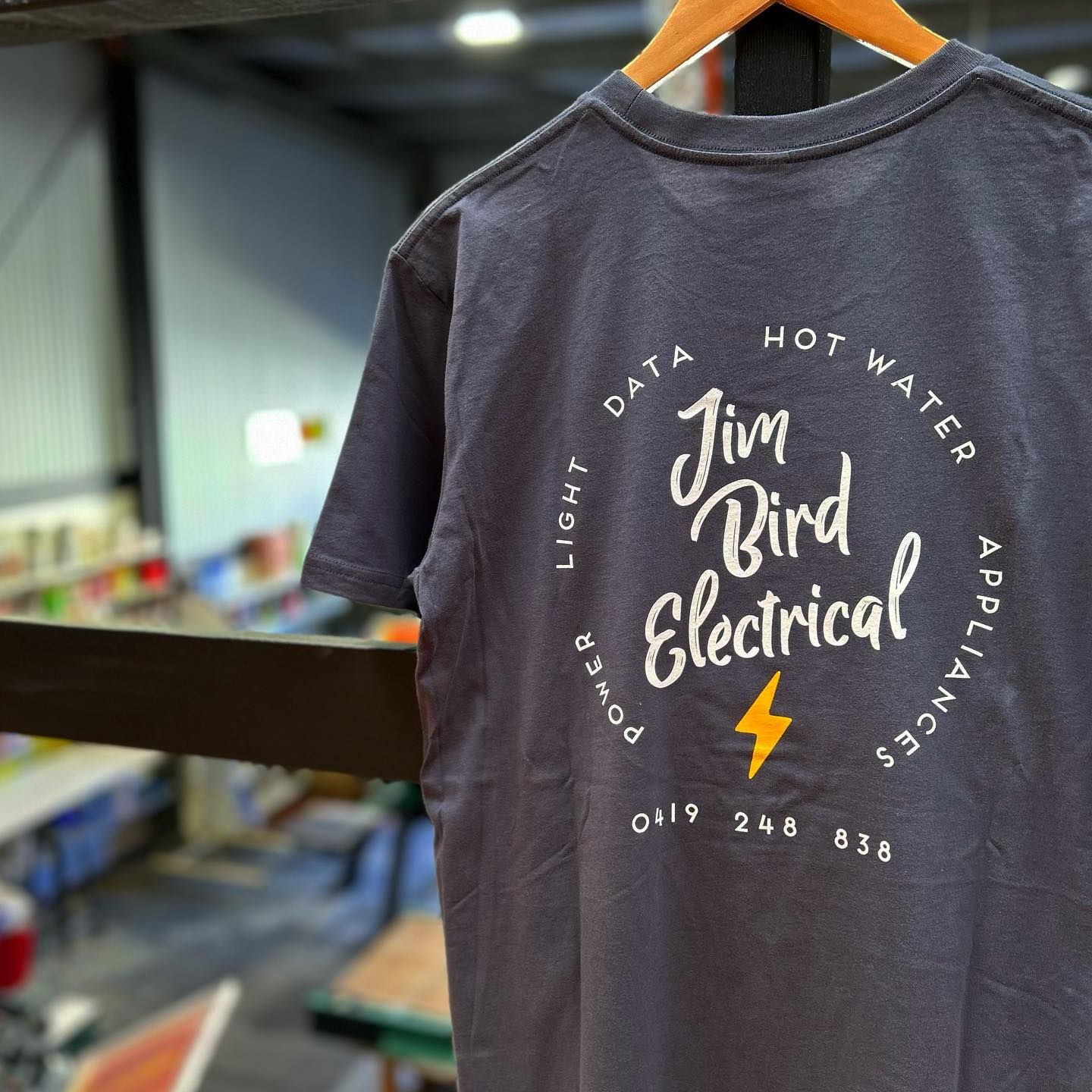 A Black Shirt with electrical branding hanging on a coathanger — Fab Art in Wallabi Point, NSW