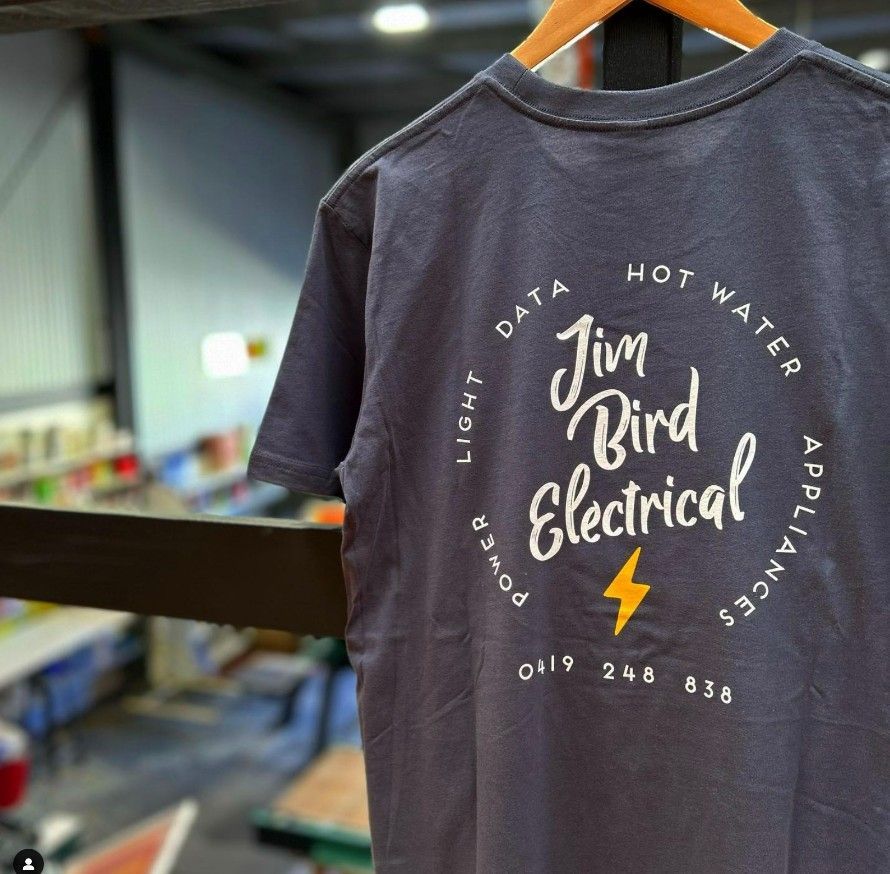 A Jim Bird Electrical T-shirt is Hanging on a Hanger — Fab Art in Wallabi Point, NSW