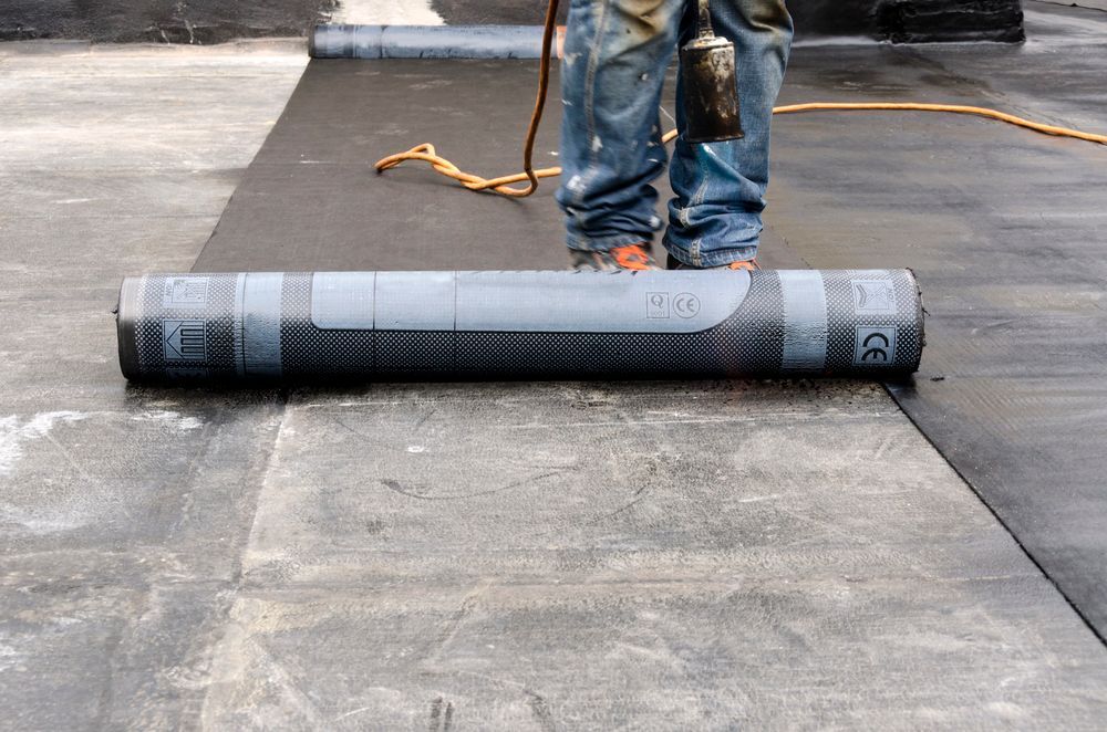 Persona che installa il materiale di copertura con una fiamma su un tetto piano.