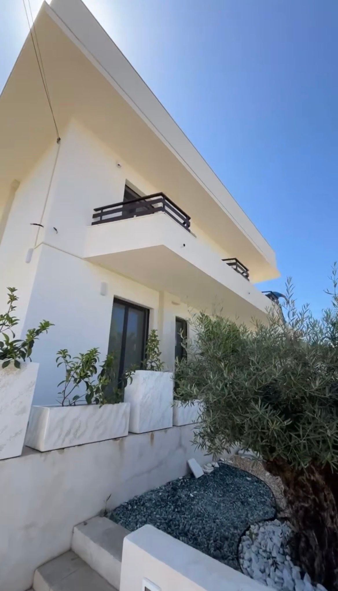 Un operaio edile con un giubbotto di sicurezza giallo tiene in mano delle planimetrie arrotolate all'esterno di un edificio in costruzione.