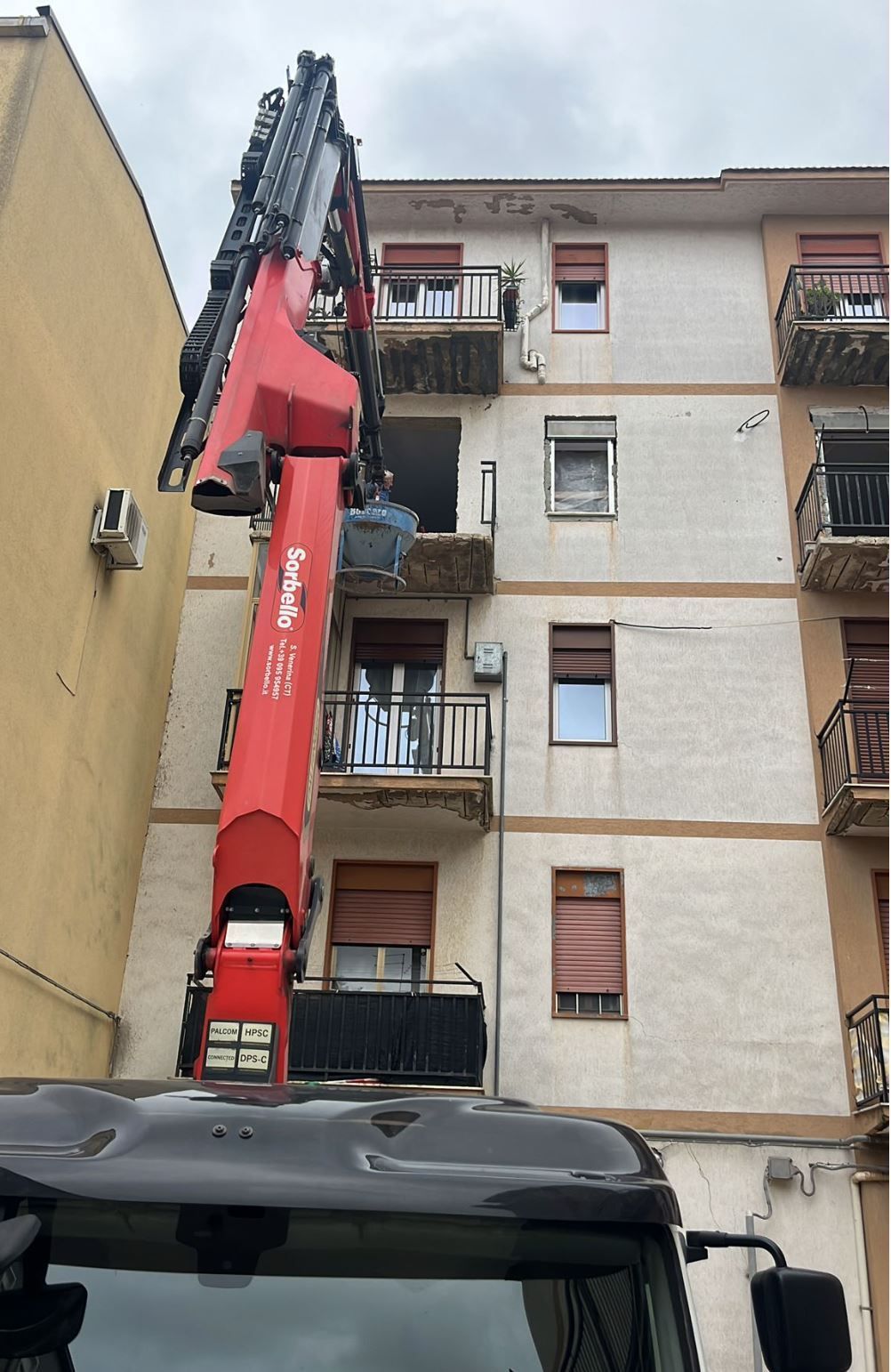 Diverse piattaforme aeree e bracci di sollevamento dai colori vivaci si stagliano contro un cielo luminoso.
