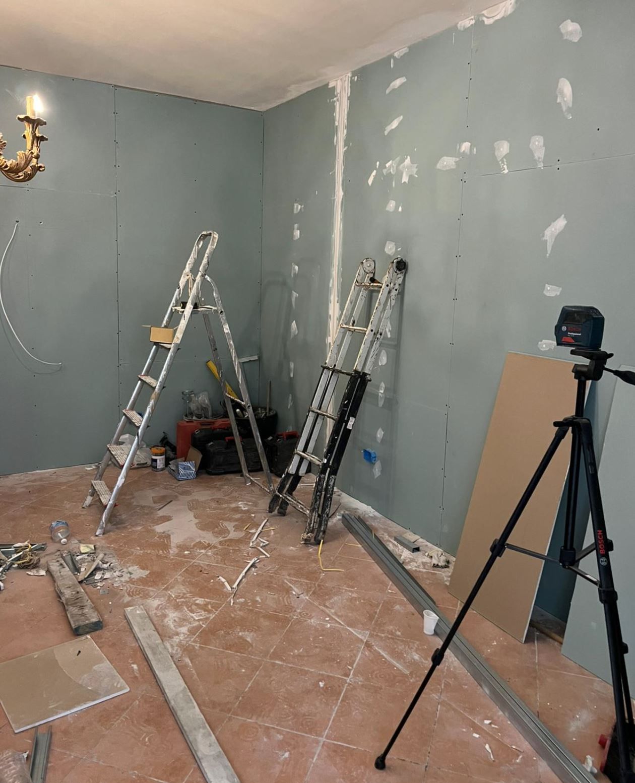 Operai edili su un tetto, mentre installano supporti in legno vicino a un muro di mattoni, con un camino e un lucernario.