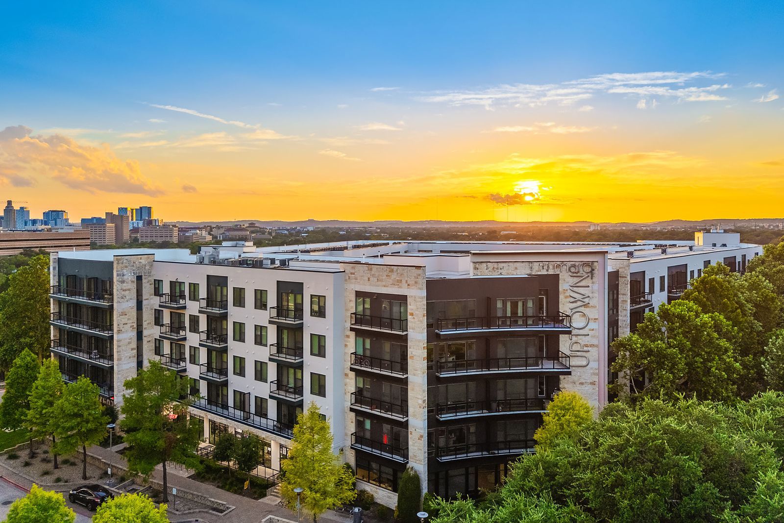 Sunset over modern apartment buildings with trees in the foreground