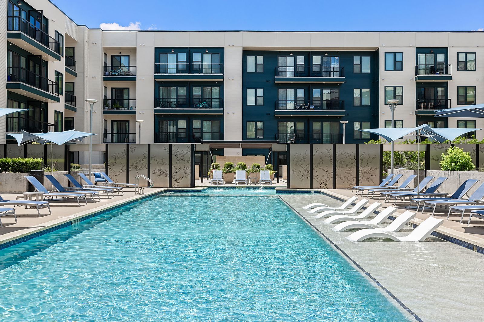 Modern apartment pool courtyard with turquoise water, lounge chairs, and glass-front buildings