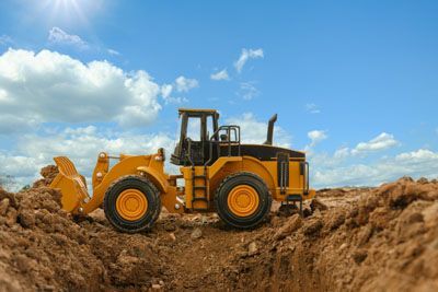 A yellow bulldozer is digging a hole in the dirt.