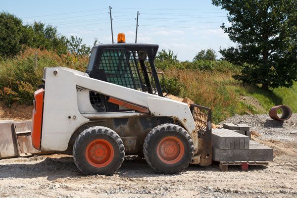 A white and orange bulldozer is parked in a dirt field.