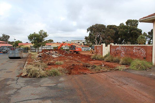 A dump truck is parked behind a fence in front of a building.