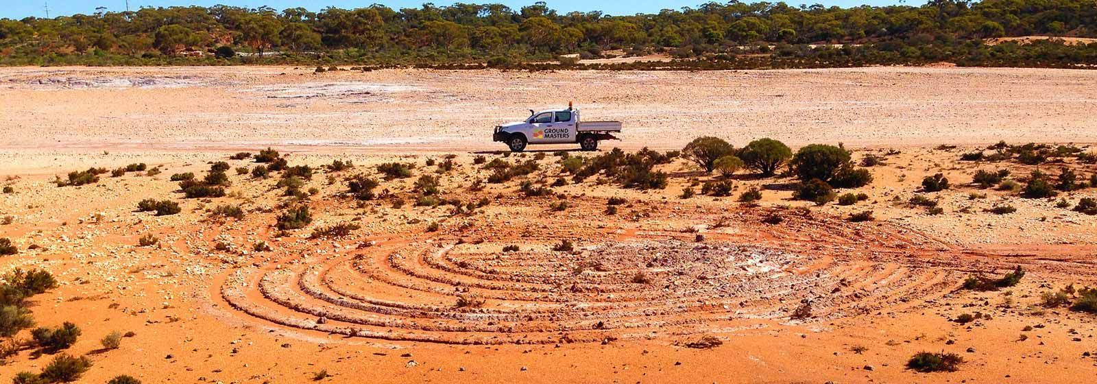 A truck is driving down a dirt road in the desert.