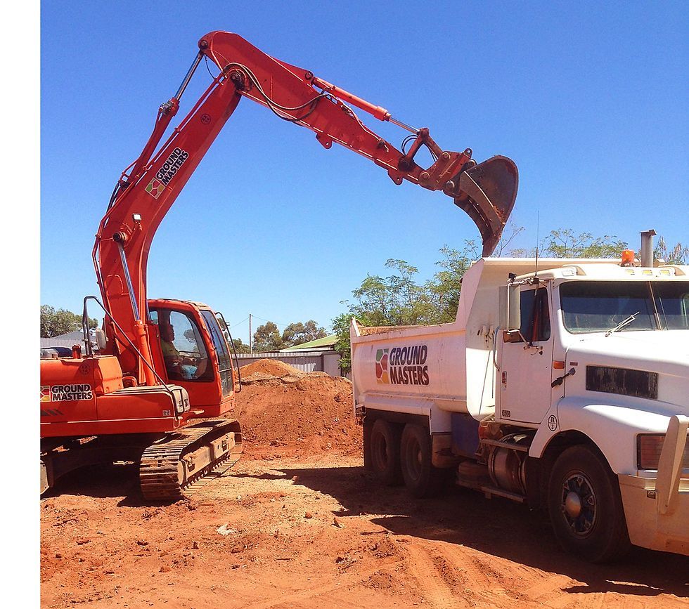 An excavator is loading dirt into a dump truck that says ground movers