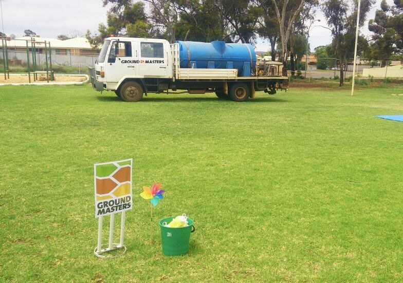 A truck is parked in a grassy field next to a sign that says ground masters