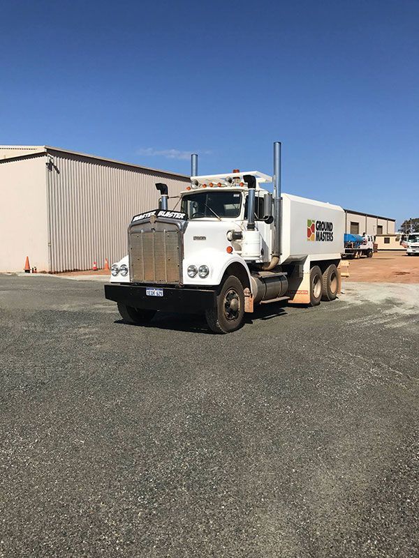 A white semi truck is parked in a parking lot in front of a building.
