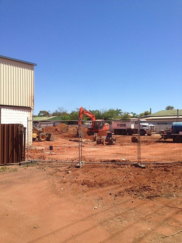 A construction site with a fence and a bulldozer in the background.