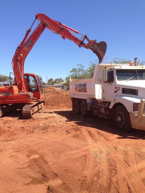 An excavator is loading dirt into a dump truck.