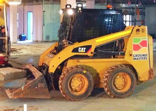 A yellow cat skid steer is parked in a garage