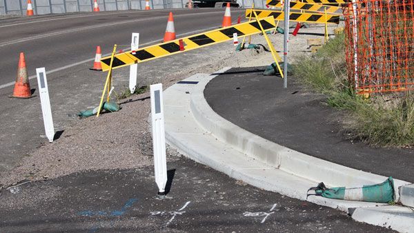 A concrete curb is being built on the side of a road.