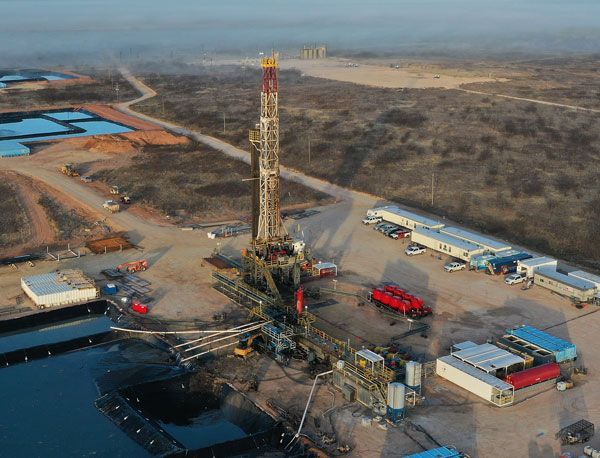 An aerial view of an oil rig in the middle of a field.