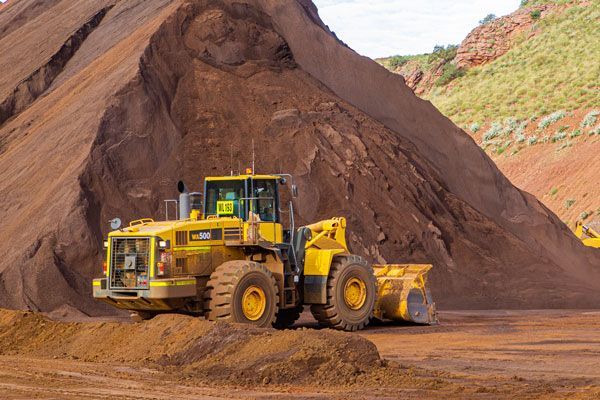 A yellow bulldozer is driving in front of a pile of dirt.