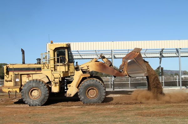 A yellow bulldozer is loading dirt into a bucket