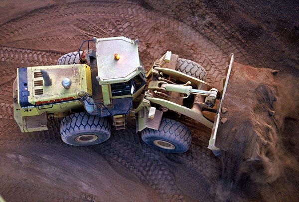 An aerial view of a bulldozer moving dirt in a dirt field