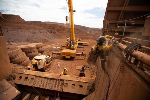 A large yellow crane is being used to lift a large piece of metal.