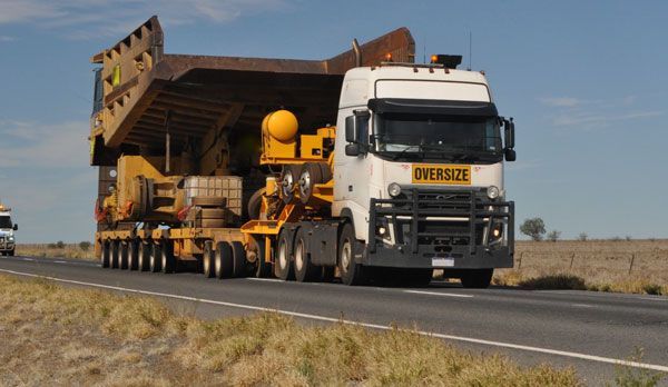 A large truck is driving down a road carrying a bulldozer.