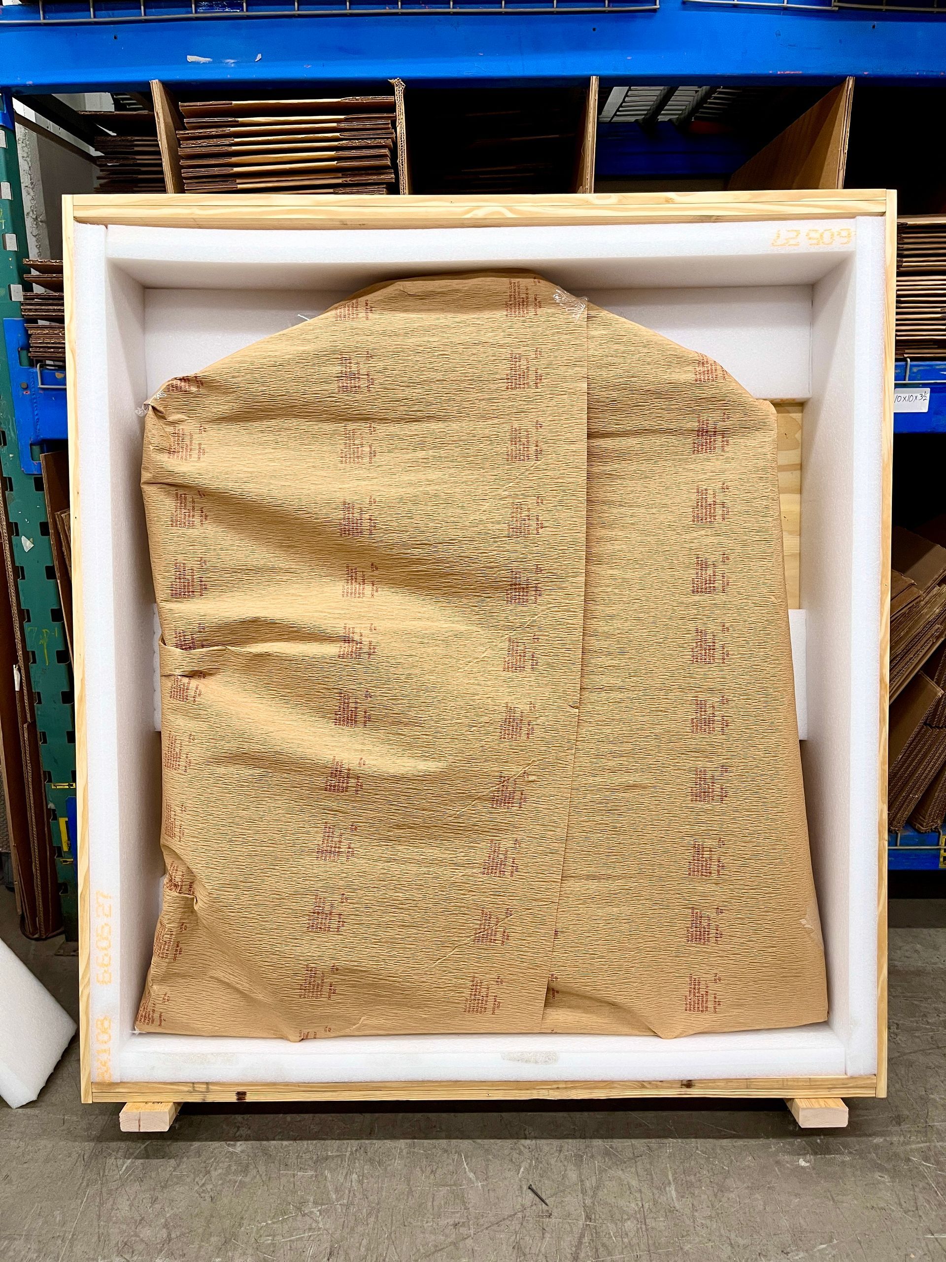 A crate, its front open, lined with foam, the wrapped sign now placed inside