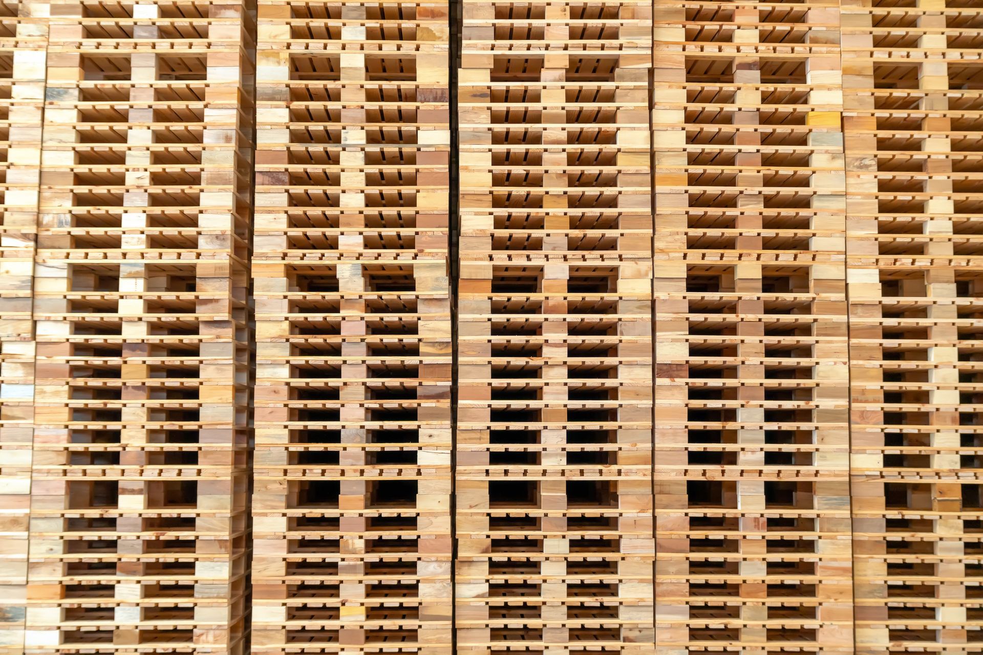 A large group of stacked wooden pallets in a warehouse.