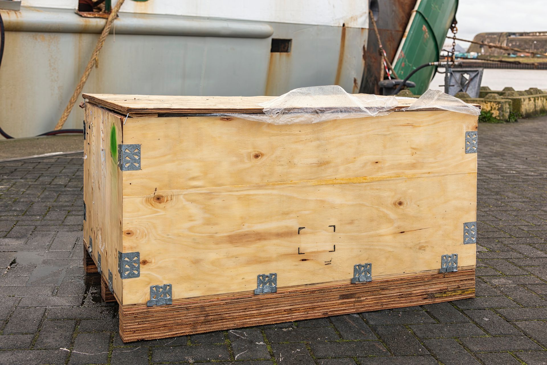 View of a wooden crate with metal fittings in the outdoors. View of a wooden crate with metal fittings in the outdoors.