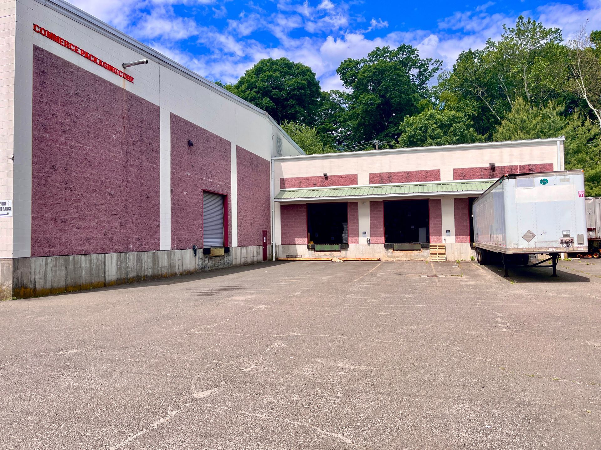 Commerce Packaging's loading docks. Two are open, leading to the warehouse; one has a trailer in it, and one is closed.