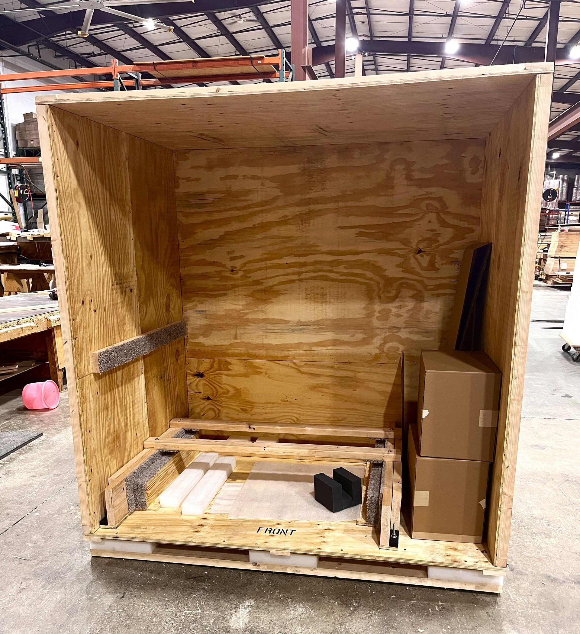 The crate we created to protect an SMT, with the front open to show off the interior. The interior has carpeted joists, heavy bolted supports, and 2” foam panels.