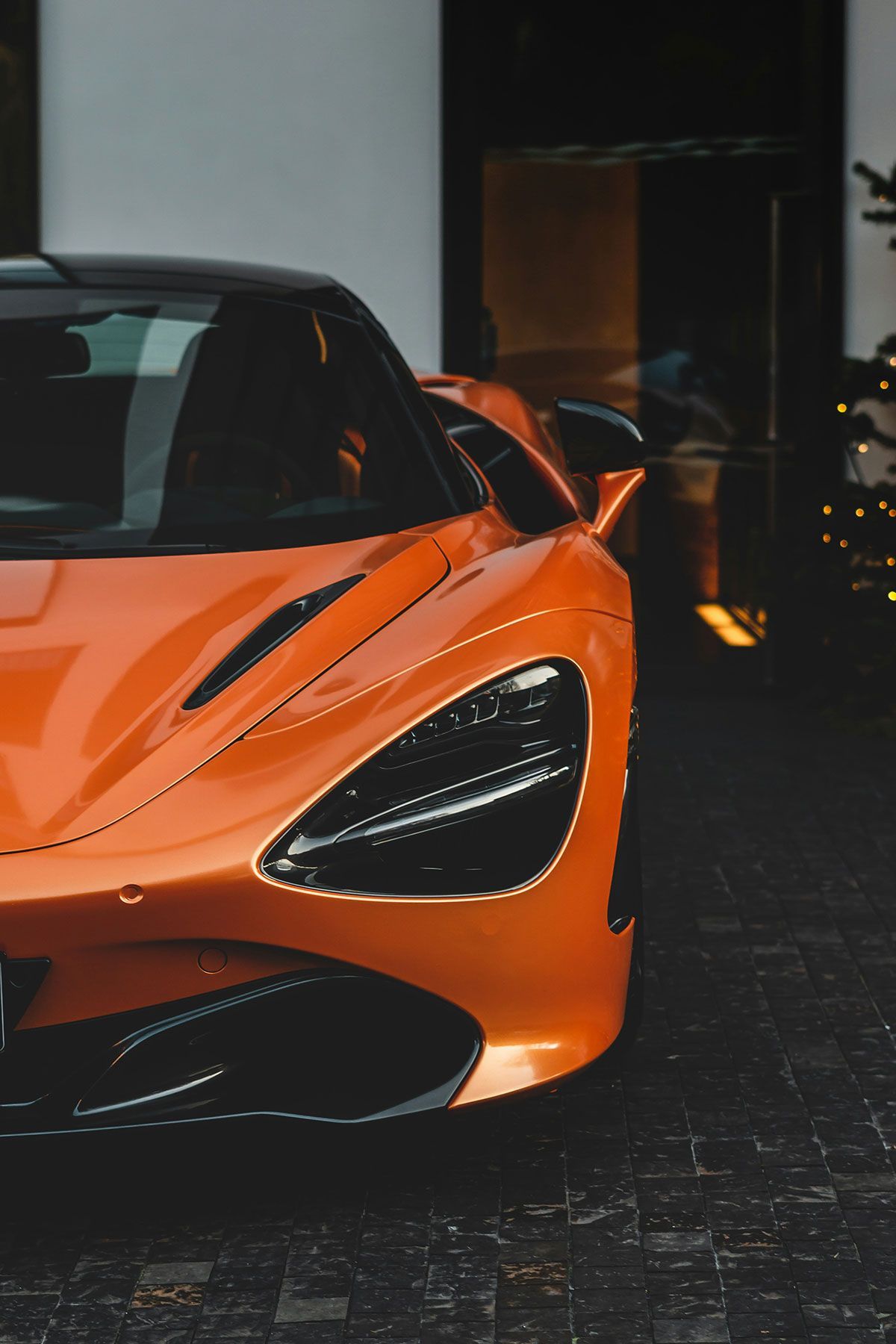 Orange McLaren sports car parked on dark textured surface.