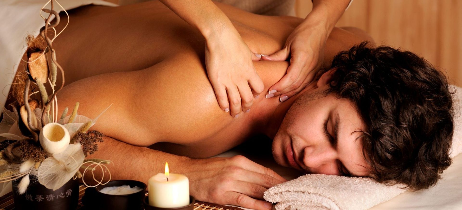 Ein Mann liegt auf einem Bett und wird von einer Frau massiert.