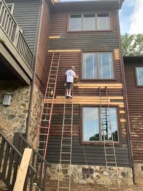 A Man On A Ladder Is Painting The Side Of A Three-Storey House – Boone, NC – A Brush Above Painting