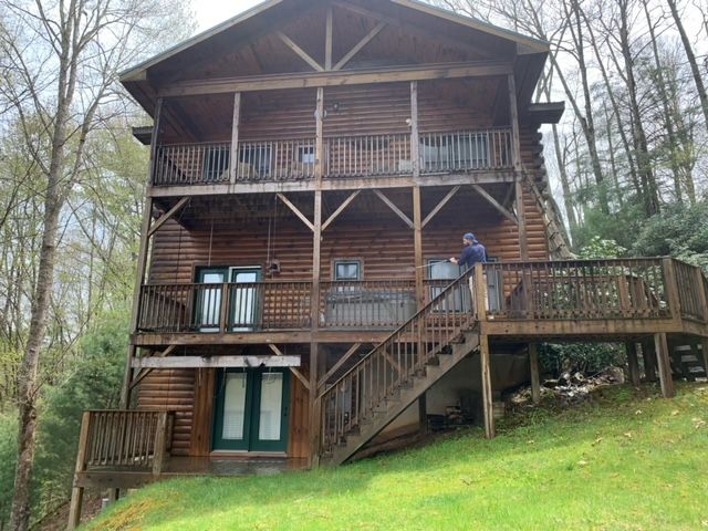 A Man Is Standing On The Deck Of A Large Log Cabin – Boone, NC – A Brush Above Painting