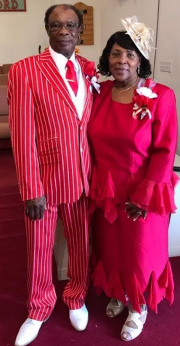 A man and a woman are standing next to each other wearing red suits.