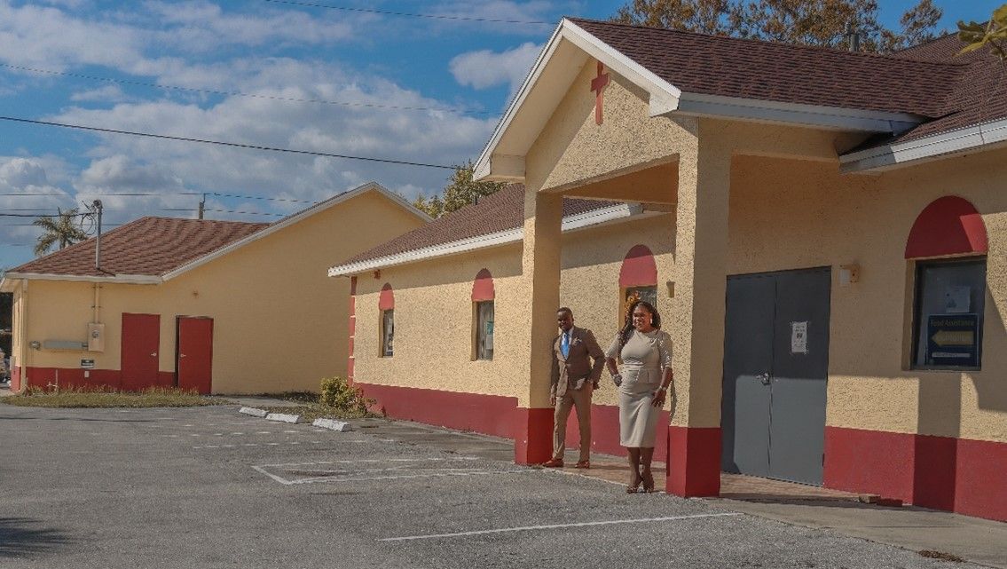 A man and a woman are standing in front of a building.