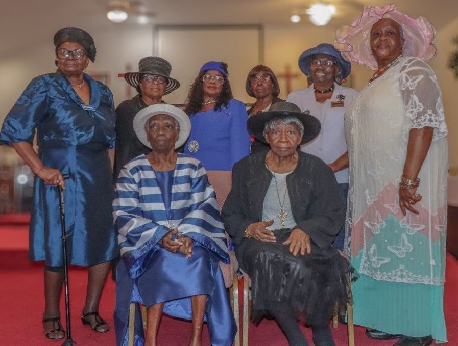 A group of older women are posing for a picture in a church.
