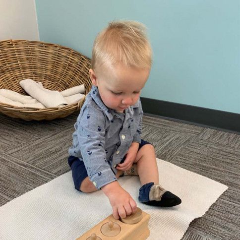 A young boy is sitting on the floor playing with a wooden toy.