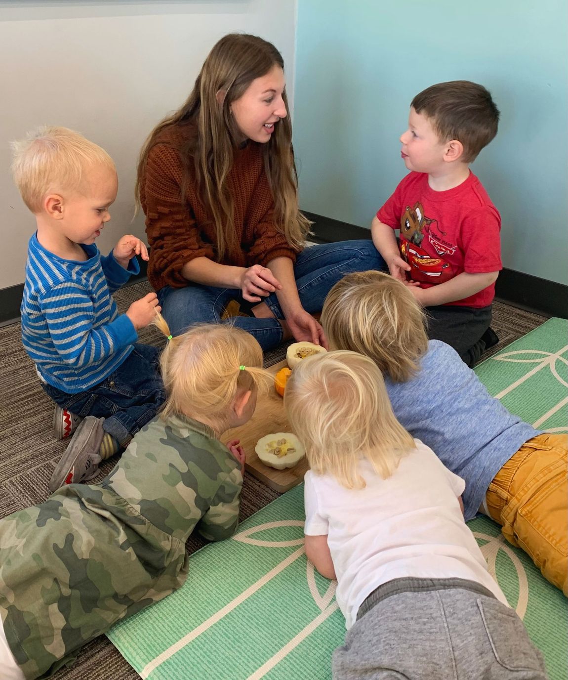 A group of children are sitting around a table playing with toys.