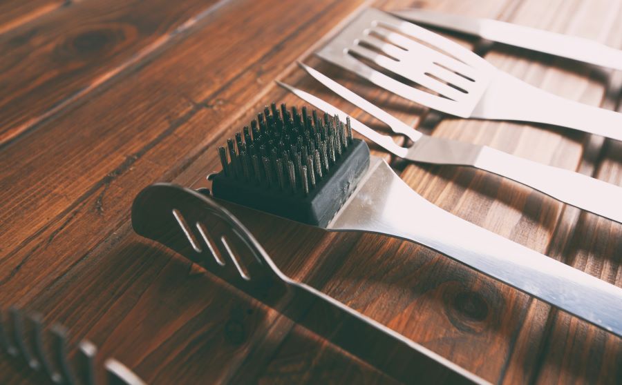 Three grilled sausages are sitting on top of a pan of vegetables.