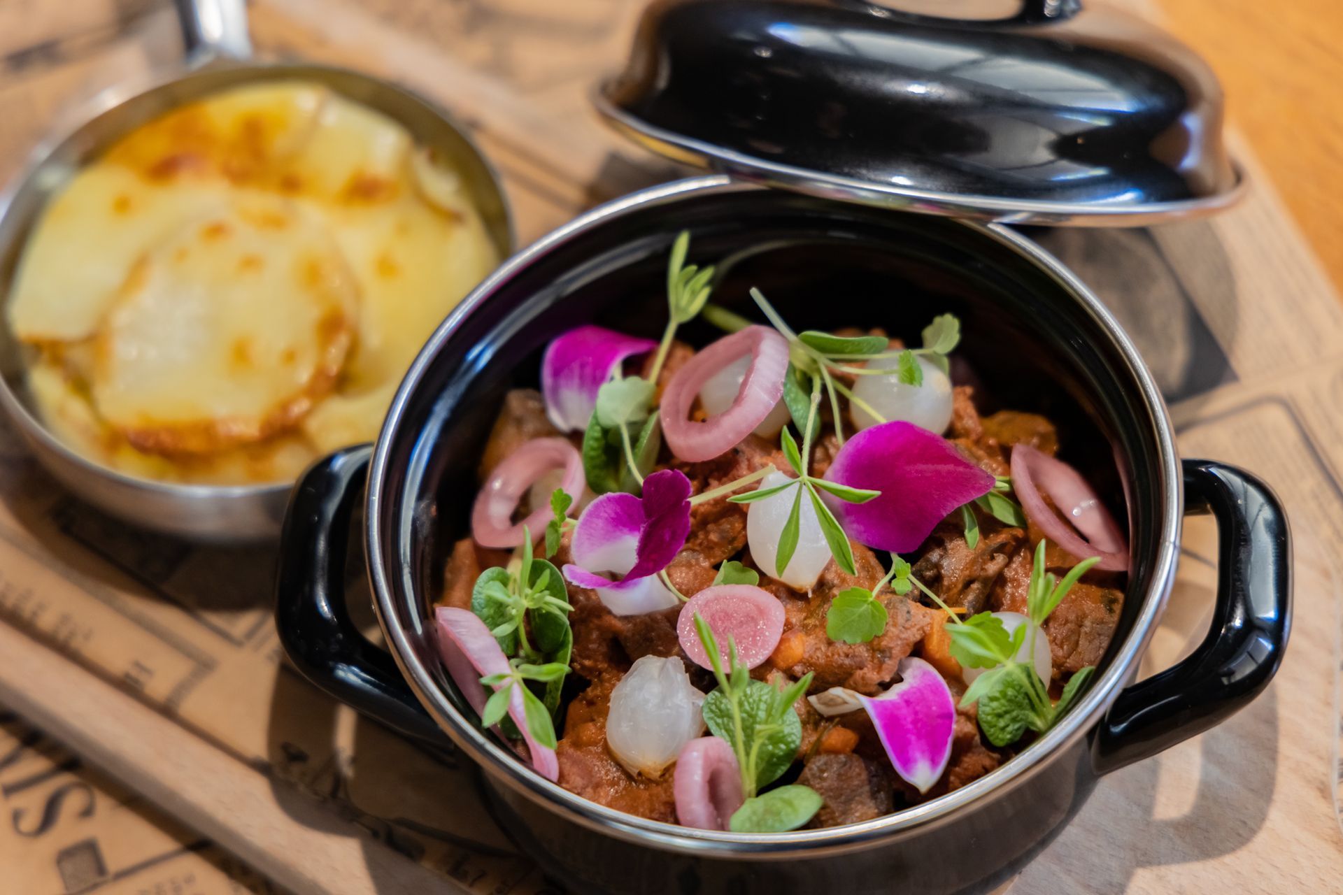 A pot of food with flowers in it is on a table next to a pan of food.
