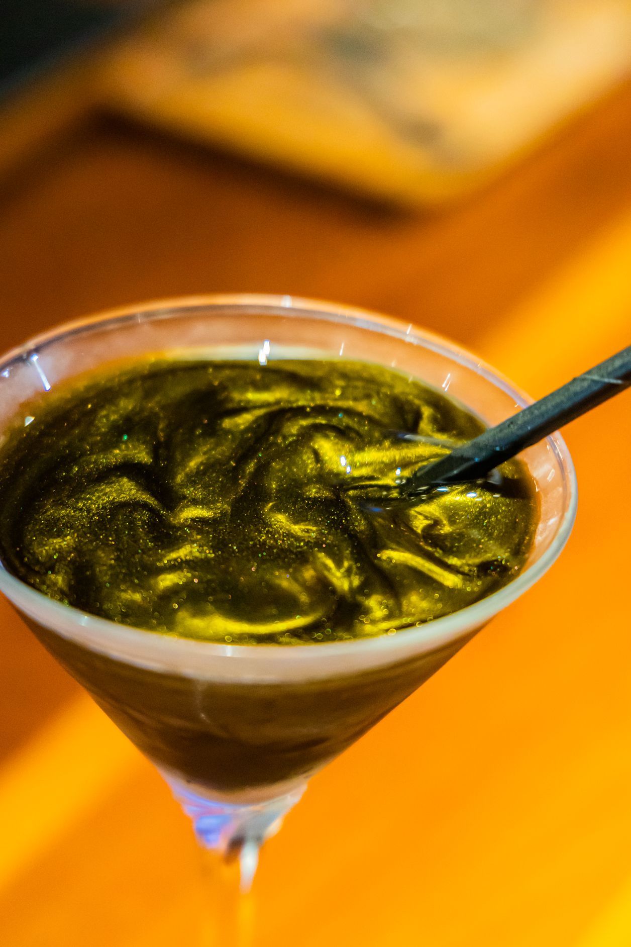 A martini glass filled with green liquid and a spoon in it.