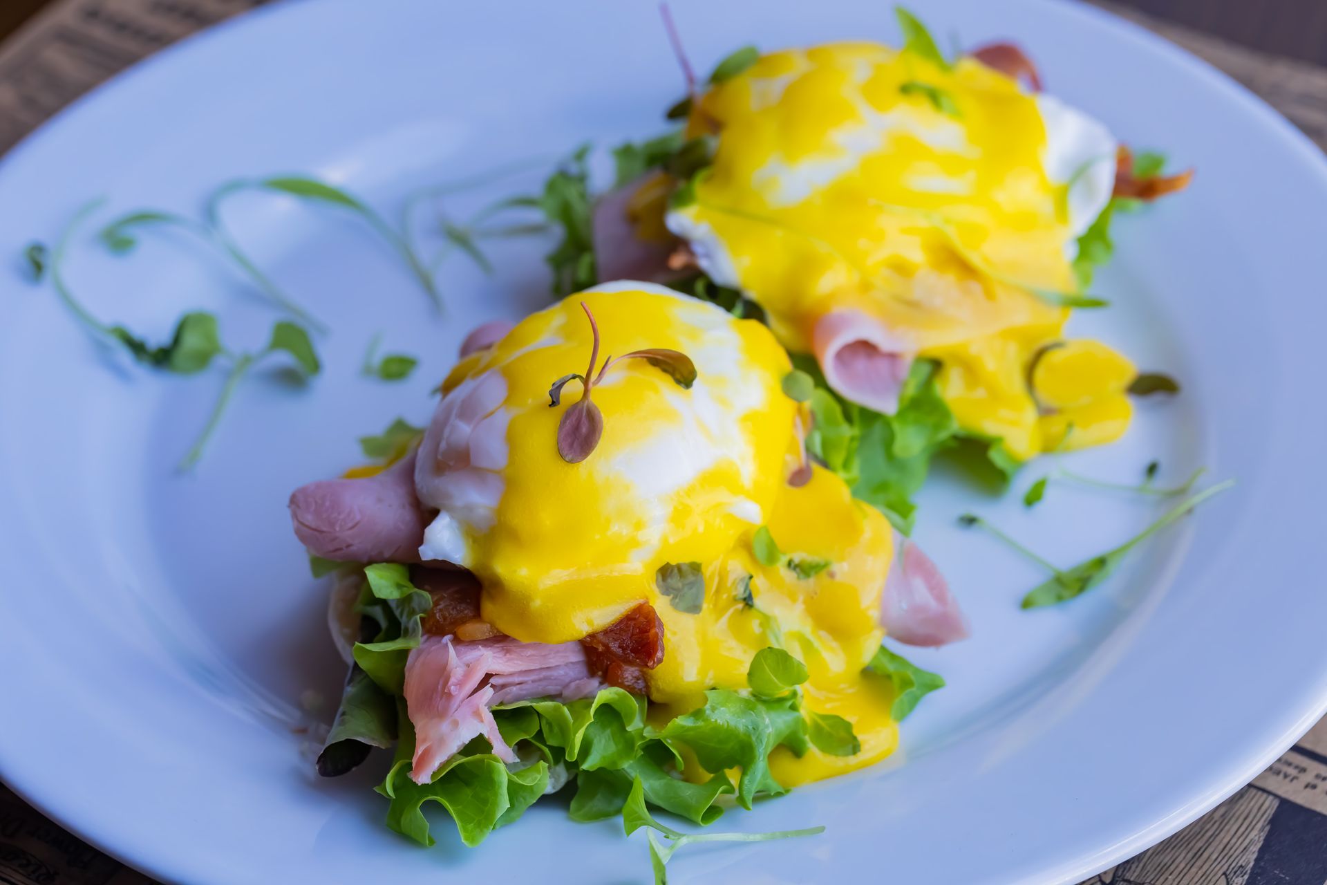A white plate topped with two poached eggs and ham.